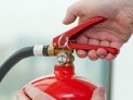 white hand presses the trigger fire extinguisher
