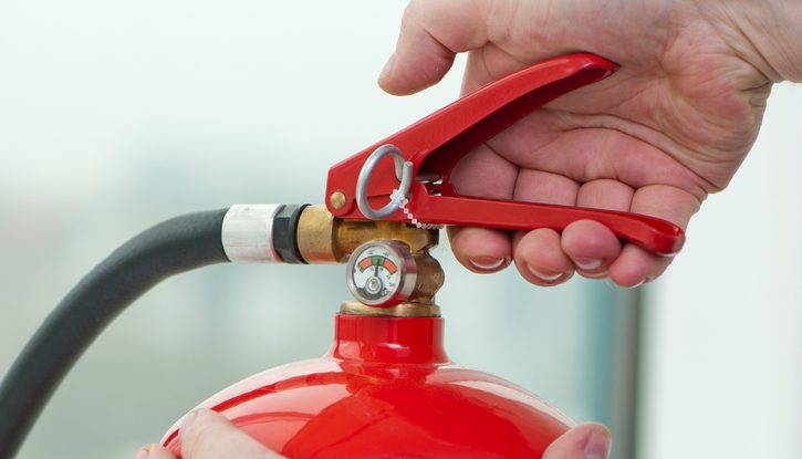 white hand presses the trigger fire extinguisher